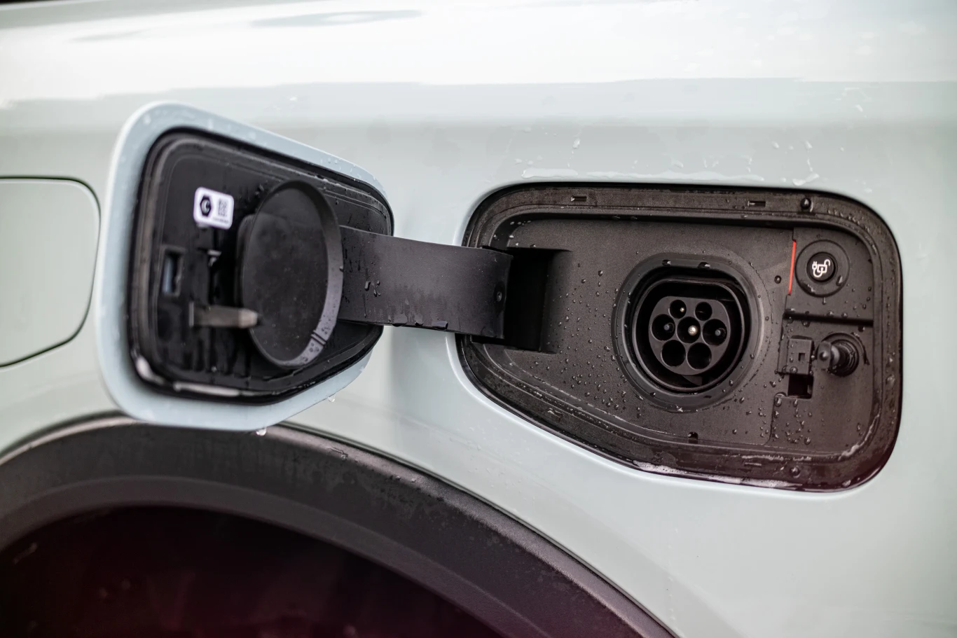 Otwarty port ładowania samochodu elektrycznego z widocznym gniazdem i klapką przy karoserii pojazdu.