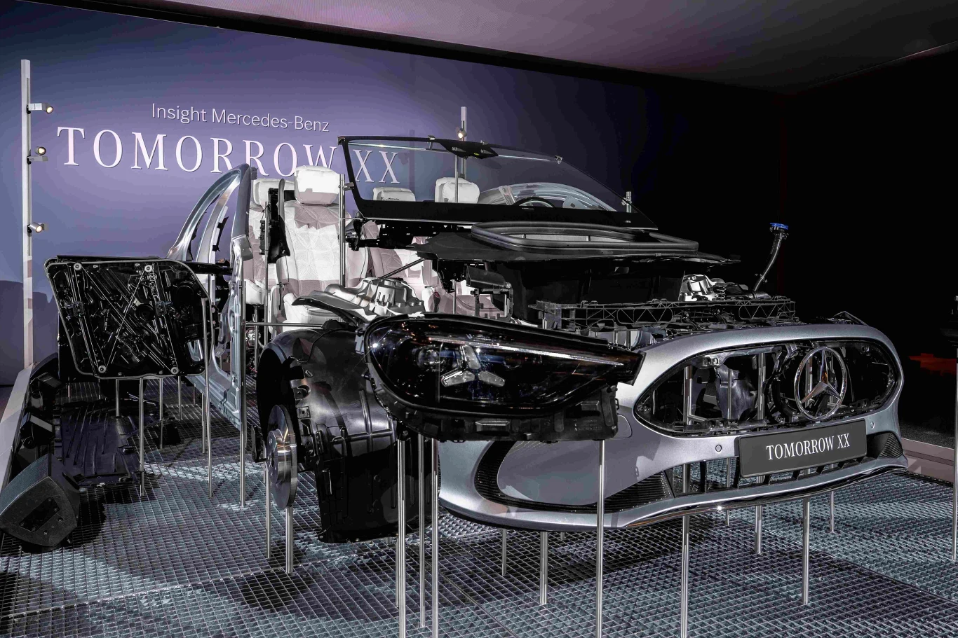 Niemiecki gigant ma plan na "Mercedesy jutra". Demonstracja przekroju samochodu luksusowego z widocznymi podzespołami wnętrza, silnika oraz elementów konstrukcyjnych, ekspozycja w nowoczesnym otoczeniu z tablicą informującą o projekcie Mercedes-Benz Tomorrow