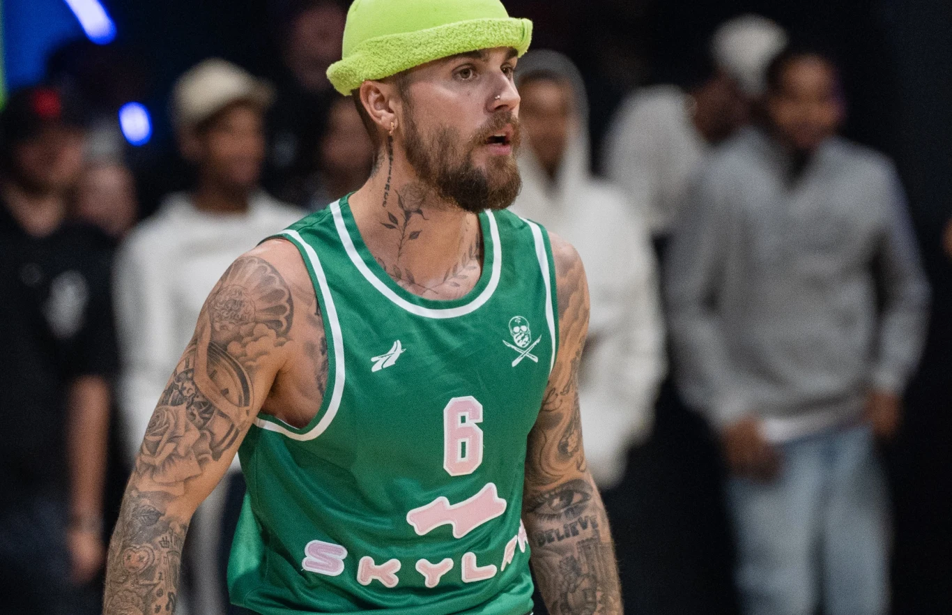 Justin Bieber dodał poruszający post na Instagram Brodaty mężczyzna w zielonym sportowym stroju z numerem 6 oraz żółtozielonej czapce z daszkiem, silnie wytatuowany na ramionach, skoncentrowany podczas gry koszykarskiej na hali. W tle rozmyta grupa widzów.