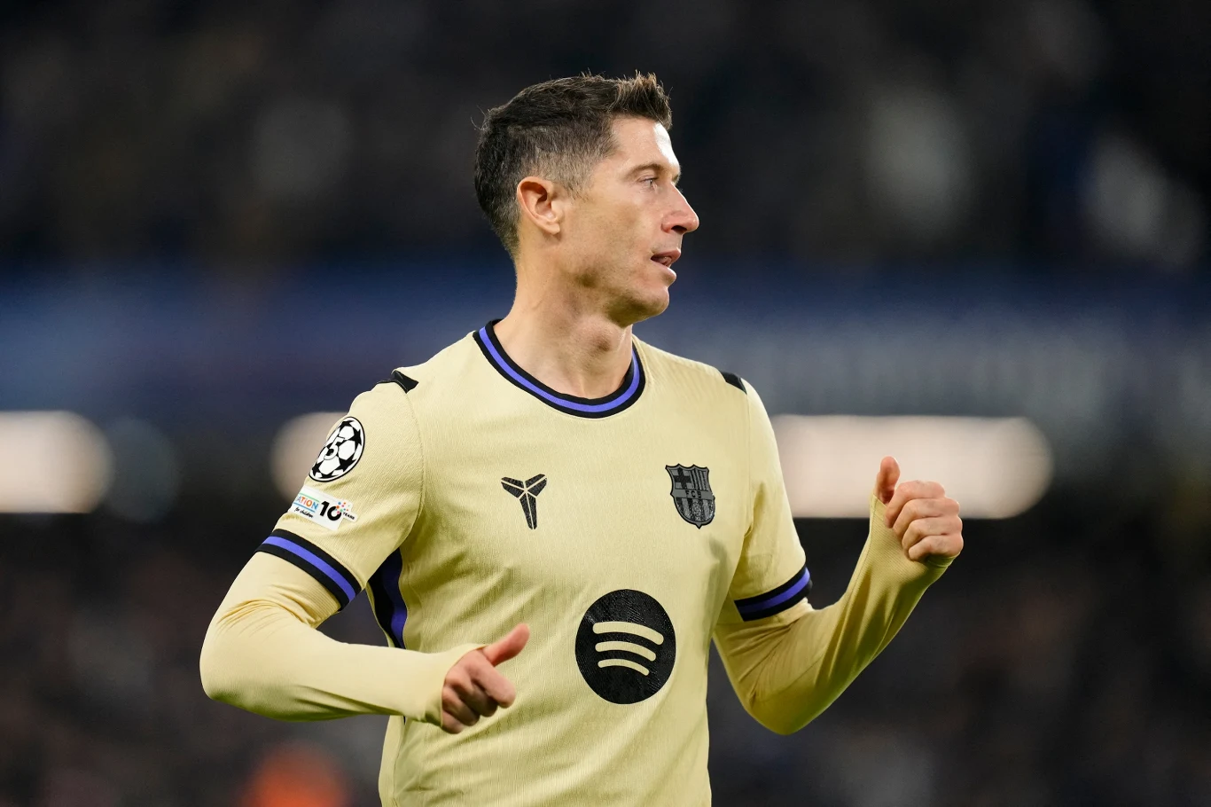 Robert Lewandowski Piłkarz w jasnożółtej koszulce FC Barcelona podczas meczu, w tle rozmyta publiczność stadionu, widoczne logo klubu oraz sponsor na koszulce, zawodnik w dynamicznej pozycji szykuje się do akcji.
