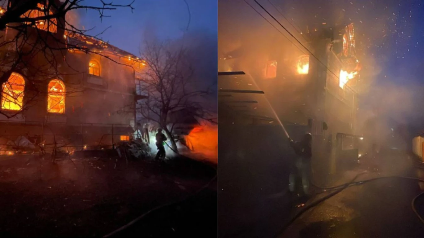 Państwowa Służba Ratunkowa Ukrainy Płonący budynek, ogień widoczny przez okna, kłęby dymu unoszące się nad konstrukcją, strażacy próbujący ugasić pożar w gęstej mgle i przy niskiej widoczności.