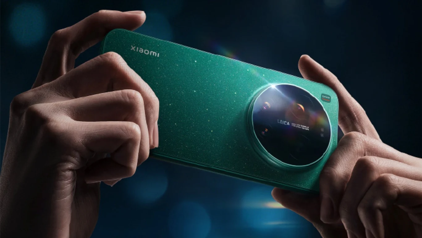 Dwie dłonie trzymają zielony smartfon marki Xiaomi wyposażony w dużą okrągłą wyspę aparatów z logo Leica; tło ciemne, rozmyte, z efektem świetlnym padającym na urządzenie.