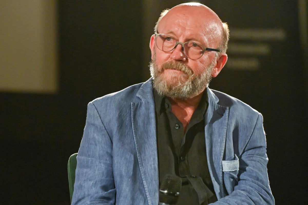 Artur Barciś Artur Barciś w jasnoniebieskiej marynarce i okularach trzyma mikrofon.