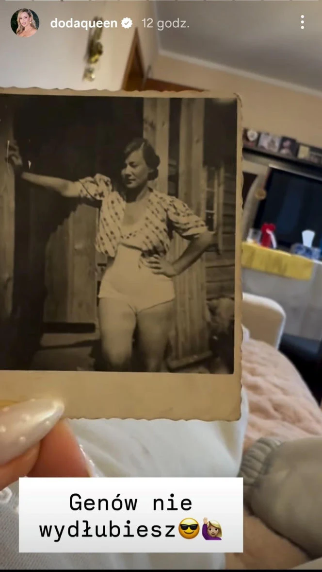 Stara, czarno-biała fotografia kobiety z ręką opartą o ścianę drewnianego budynku na tle wnętrza mieszkania. W tle widać meble, żółty obrus i inne przedmioty codziennego użytku.