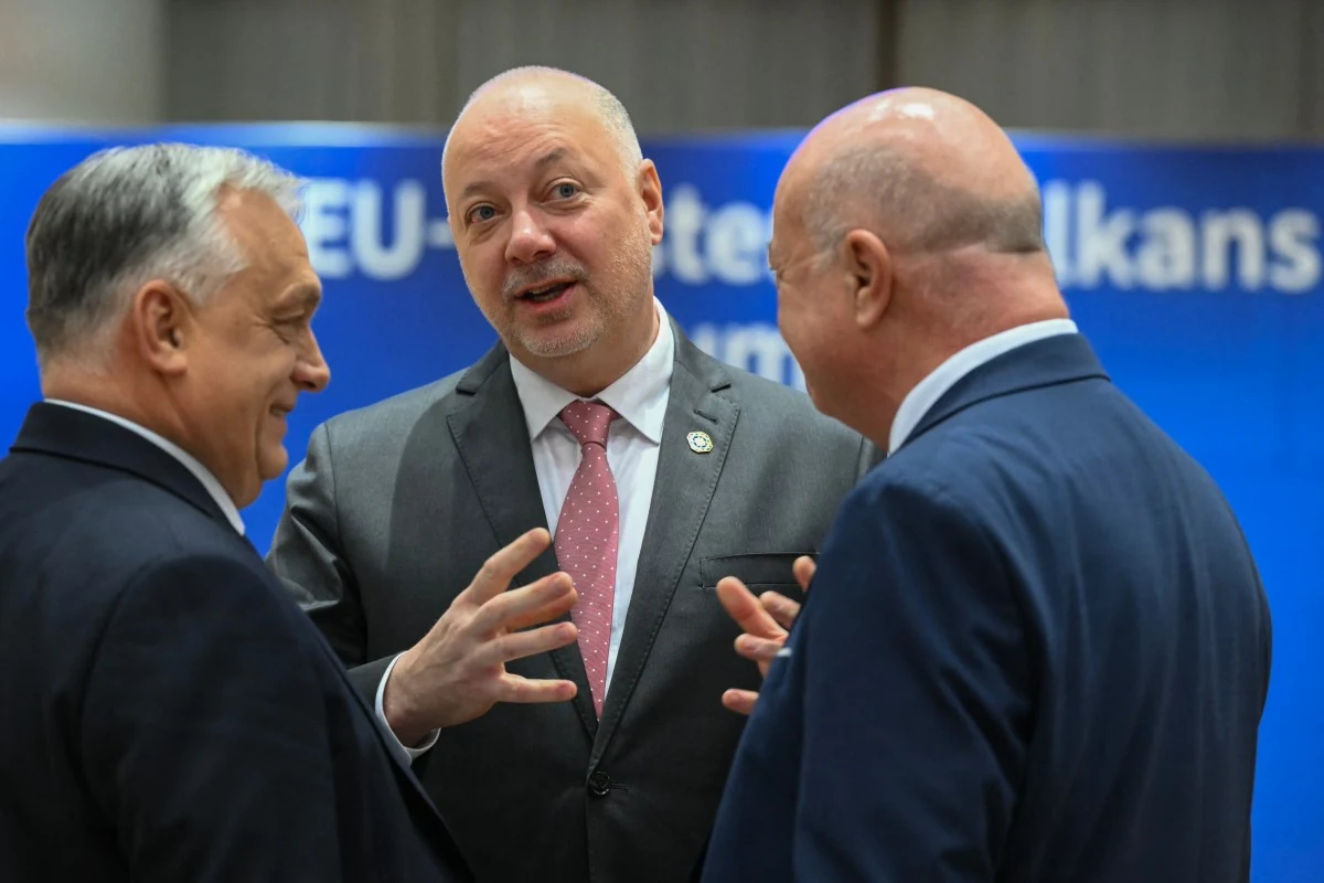 Premier Bułgarii Rosen Żelazkow podczas unijnego szczytu w Brukseli Trzech mężczyzn w garniturach prowadzi ożywioną rozmowę w formalnym otoczeniu, jeden z nich gestykuluje rękami, a w tle widoczny niebieski baner z napisem EU.