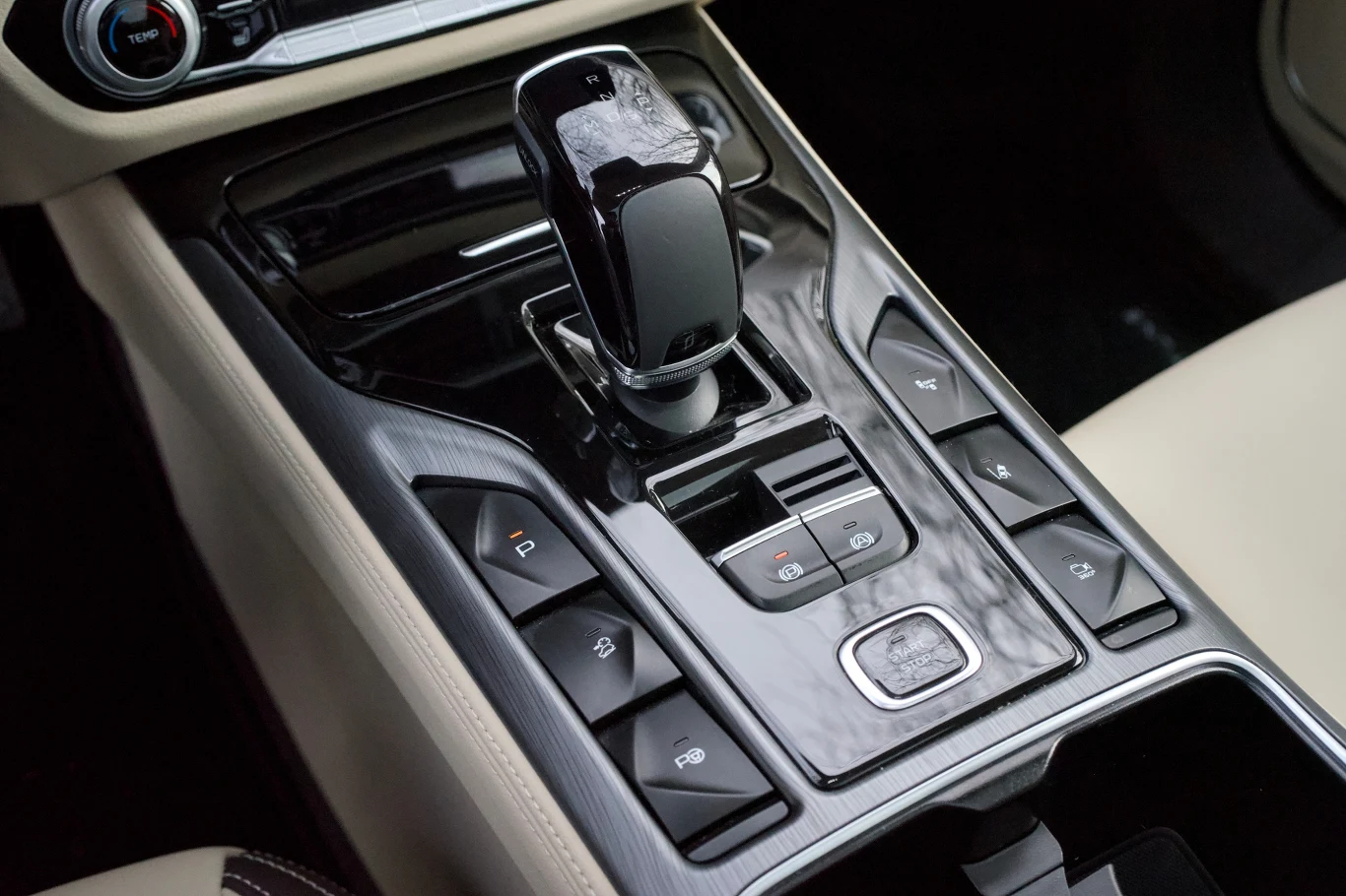 Panel sterowania automatycznej skrzyni biegów z licznymi przyciskami i nowoczesną dźwignią zmiany biegów, wykończony materiałami wysokiej jakości.