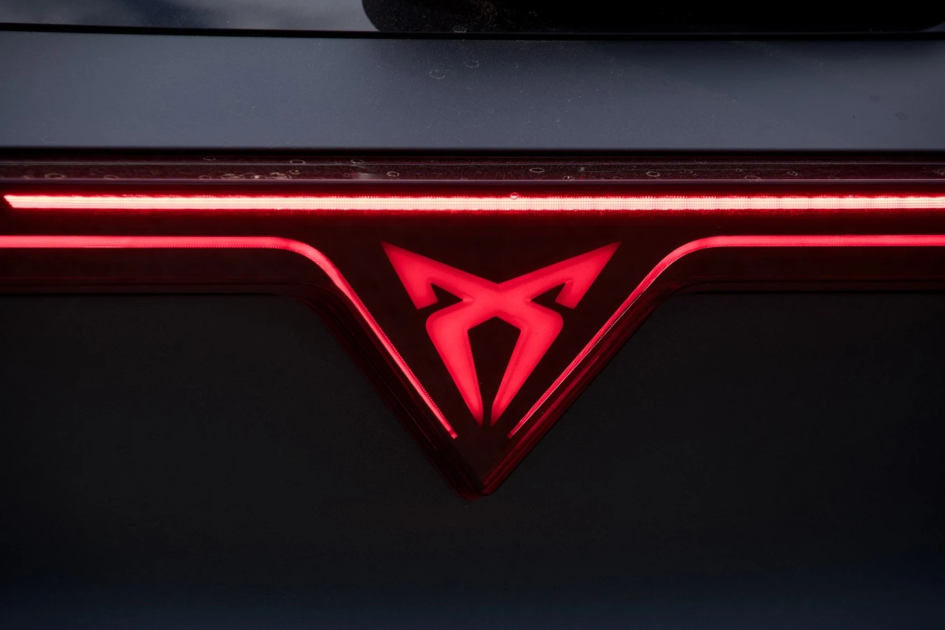 Jasnoczerwone światła LED tworzą futurystyczny wzór wraz z charakterystycznym, świecącym logotypem na tle ciemnej karoserii pojazdu.