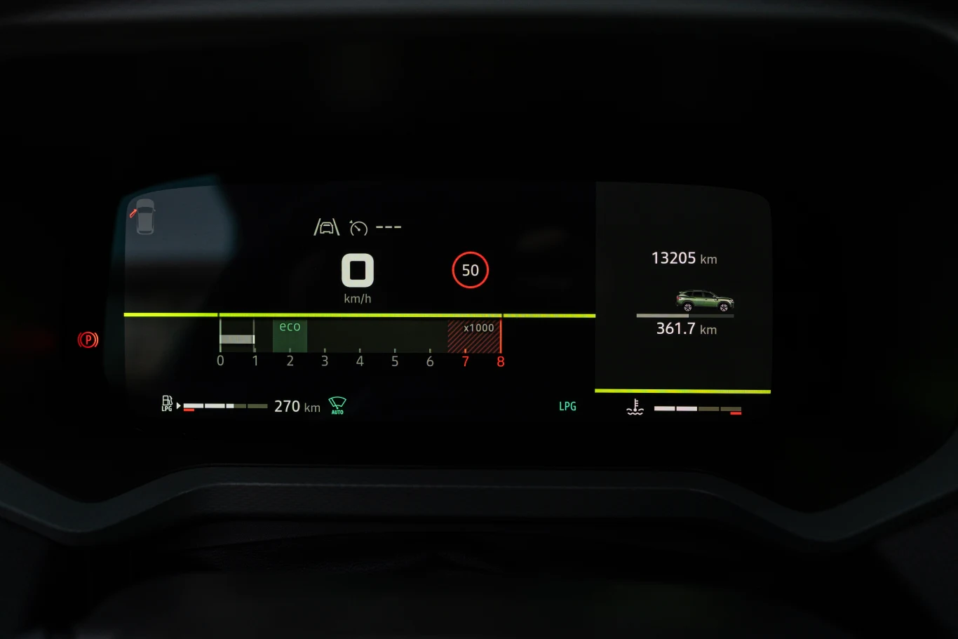 Cyfrowy wyświetlacz samochodu z prędkościomierzem w centralnej części, informacjami o spalaniu, zasięgu na paliwie, aktualnym przebiegu oraz wskaźnikiem trybu jazdy ECO.