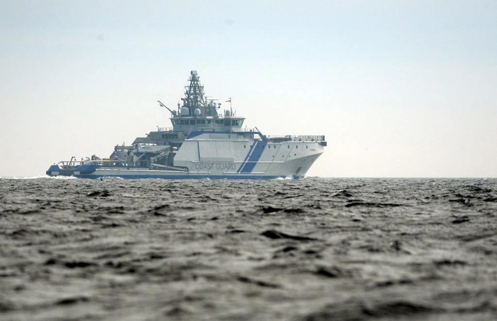 Statek patrolowy Turva uczestniczył w inspekcji jednostki podejrzanej o uszkodzenie podmorskiego kabla łączącego Helsinki z Tallinem Duży biały statek patrolowy straży granicznej płynący po lekko wzburzonym morzu, widoczny z oddali na tle jasnego nieba.