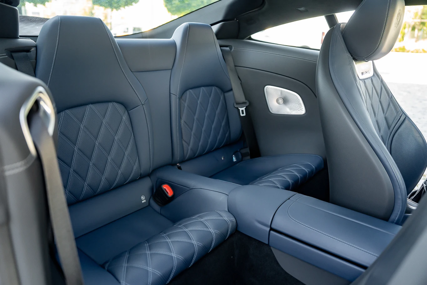 Luksusowe tylne siedzenia samochodu z wysokiej jakości niebieską skórzaną tapicerką i kontrastowym pikowaniem, wyraźne przeszycia, środkowy podłokietnik, wykończenie wnętrza w klasycznym stylu.