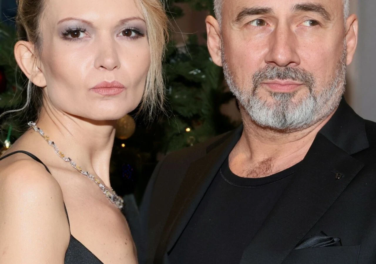 Agnieszka Kustosz, Jacek Kopczyński Dwoje dorosłych ludzi w eleganckich strojach pozujących razem na tle choinki, kobieta w czarnej sukience z naszyjnikiem, mężczyzna w marynarce z siwą brodą.