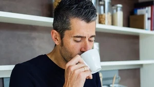 Mężczyzna około 40 lat pije z filiżanki, stoi w kuchni