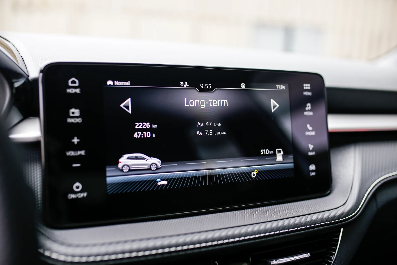 Cyfrowy ekran dotykowy w nowoczesnym samochodzie wyświetlający statystyki długoterminowe jazdy, takie jak przebyty dystans, średnia prędkość, średnie spalanie i zasięg. Elegancka deska rozdzielcza z wyraźnym, czytelnym interfejsem.
