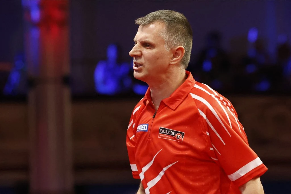 Krzysztof Ratajski zabrał głos po ćwierćfinale MŚ Mężczyzna w czerwonej koszulce sportowej z wyraźnym wyrazem napięcia na twarzy, stojący w hali sportowej, na rozmytym tle widoczne sylwetki obserwatorów.