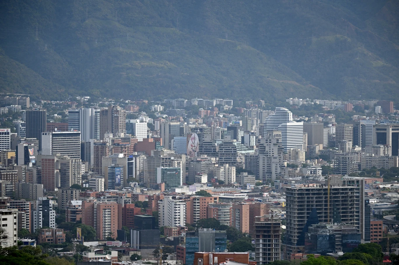 Caracas, stolica Wenezueli Panorama dużego miasta z licznymi nowoczesnymi budynkami i wieżowcami, w tle góry stanowiące naturalną granicę oraz subtelnie zarysowane przez mgłę.
