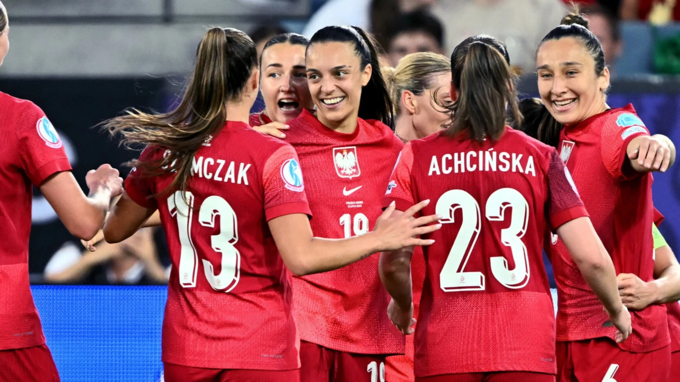 Natalia Padilla-Bidas (w środku) w barwach reprezentacji Polski Grupa polskich piłkarek w czerwonych strojach narodowych świętuje wspólnie zdobycie bramki lub wygraną. Zawodniczki uśmiechają się i okazują radość, otaczają się ramionami na tle stadionu pełnego widzów.