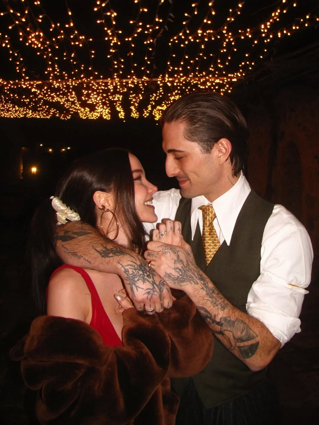 Dove Cameron i Damiano David zaręczyli się Para obejmująca się i patrząca sobie w oczy z czułością, w tle dekoracyjne światełka nadające romantyczny nastrój.