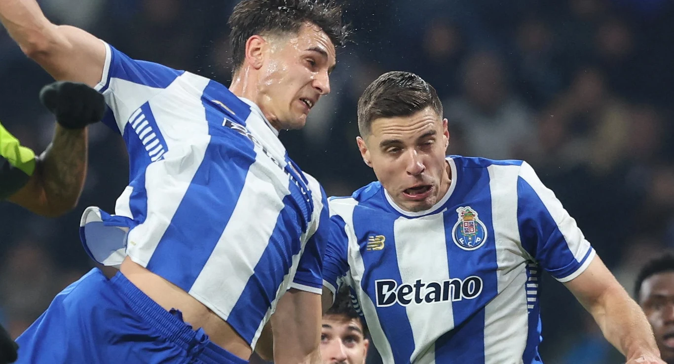 Jakub Kiwior (z lewej) i Jan Bednarek - polska para stoperów FC Porto Dwóch piłkarzy w niebiesko-białych koszulkach klubu FC Porto rywalizuje o piłkę podczas meczu, koncentrując się na walce w powietrzu, w tle widać innych zawodników.