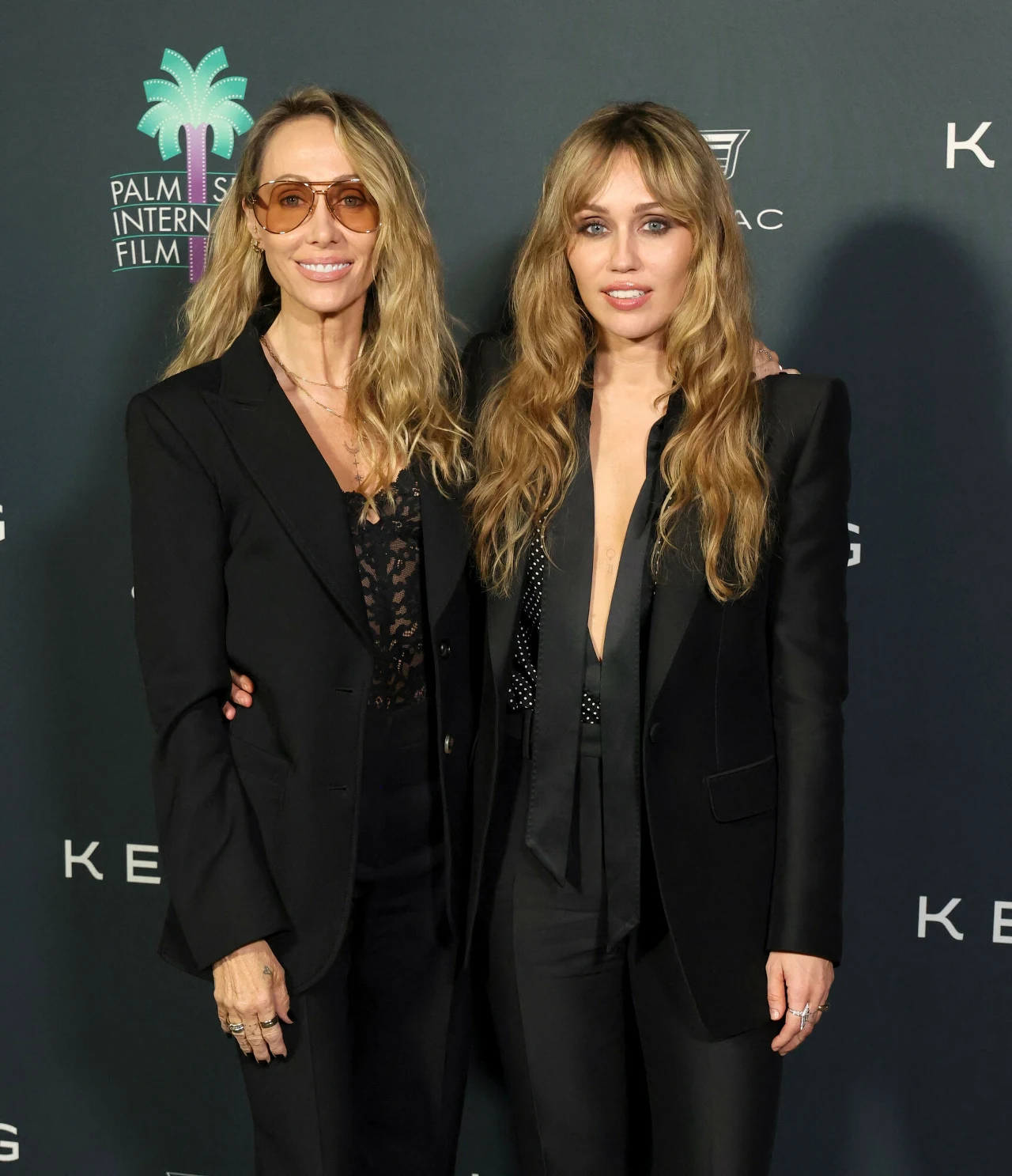 Miley Cyrus wraz z matką na galę ubrany się bardzo podobnie. Zdaniem wielu, wyglądały niczym siostry Dwie kobiety stojące obok siebie na tle ścianki z logo Palm Springs International Film Festival, ubrane elegancko w czarne garnitury, z długimi, falującymi włosami, jedna z nich ma okulary przeciwsłoneczne.