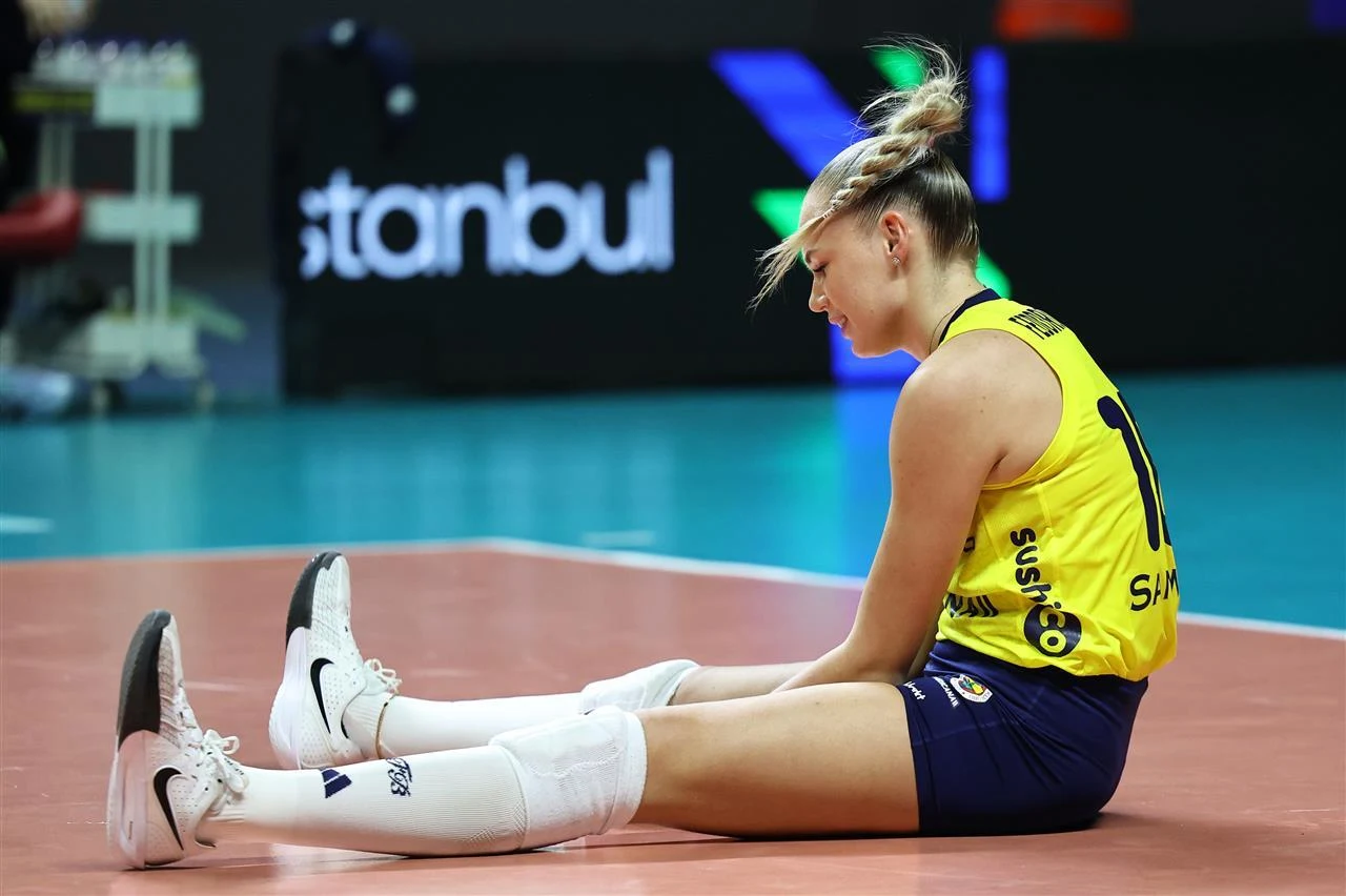 Arina Fiedorowcewa nie zagrała w Polsce Zawodniczka siatkarska w stroju zespołu siedzi na boisku, trzymając wyprostowane nogi przed sobą, na jej twarzy widoczny jest wyraz zmęczenia lub rozczarowania, w tle rozmazana ławka oraz napisy reklamowe.