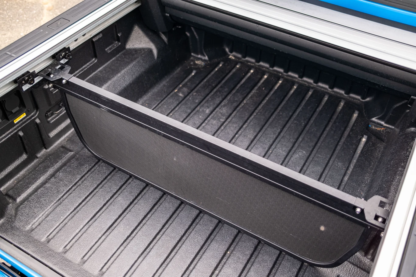 Otwarty bagażnik samochodu typu pick-up z widoczną przegrodą oddzielającą przestrzeń ładunkową, wnętrze czyste i dobrze utrzymane, detale wykończenia w czarnym kolorze.