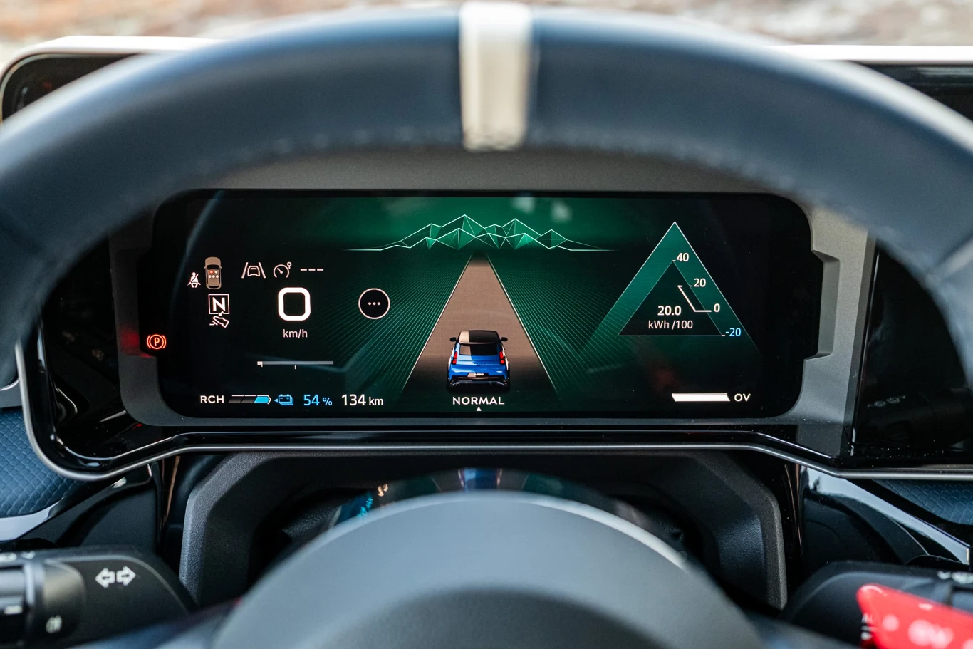 Cyfrowy ekran samochodowy wyświetla informacje dotyczące aktualnej prędkości, zużycia energii, poziomu naładowania baterii oraz przewidywanego zasięgu pojazdu elektrycznego. Na centralnej części ekranu graficzna wizualizacja drogi, otoczona wykresami o...