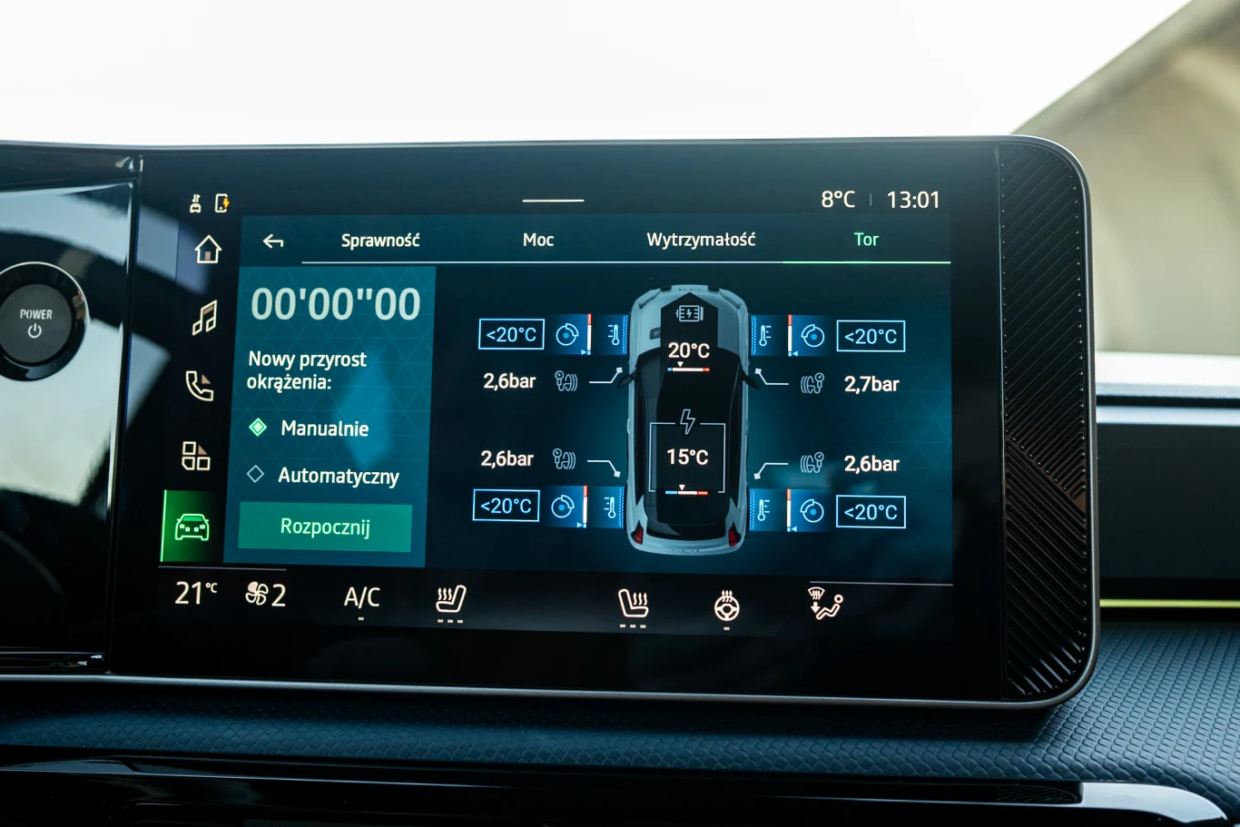 Ekran systemu multimedialnego samochodu pokazuje pomiary ciśnienia i temperatury w oponach, ustawienia klimatyzacji oraz różne parametry pojazdu. Interfejs cyfrowy jest czytelny, z kolorowymi wskaźnikami i ikonami.