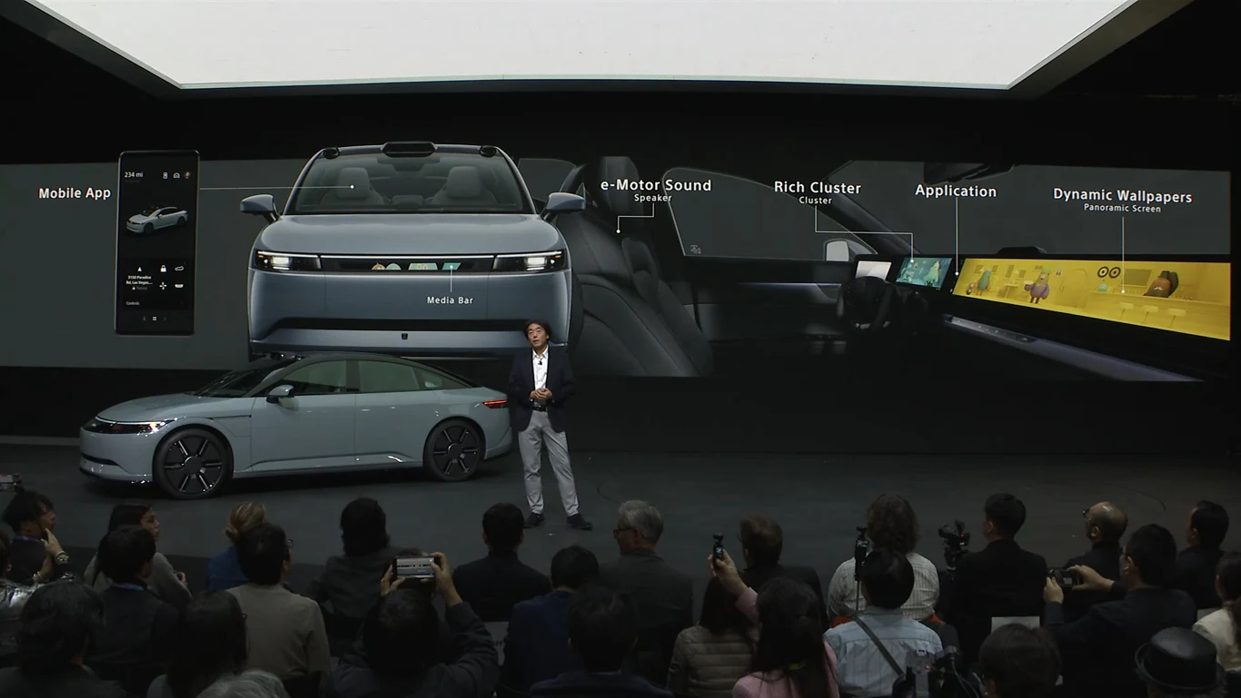 Spersonalizować motywami PlayStation (i innymi) będzie można nie tylko wnętrze pojazdu Prezentacja nowoczesnego samochodu elektrycznego na tle dużego ekranu multimedialnego, na którym wyświetlane są funkcjonalności pojazdu, takie jak aplikacje mobilne, dźwięk silnika, cyfrowa deska rozdzielcza i dynamiczne tapety. Przed samochodem stoi p...