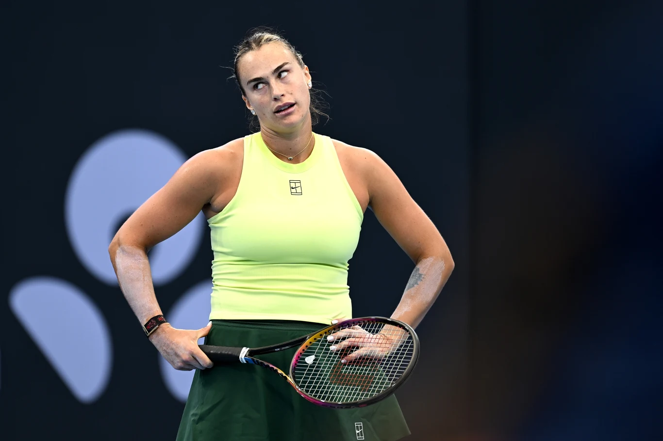 Aryna Sabalenka w meczu z Soraną Cirsteą. Brisbane 2026 Zawodniczka tenisowa w żółtej koszulce i zielonej spódniczce stoi na korcie, trzymając rakietę i wyrażając frustrację poprzez mimikę twarzy oraz postawę ciała.