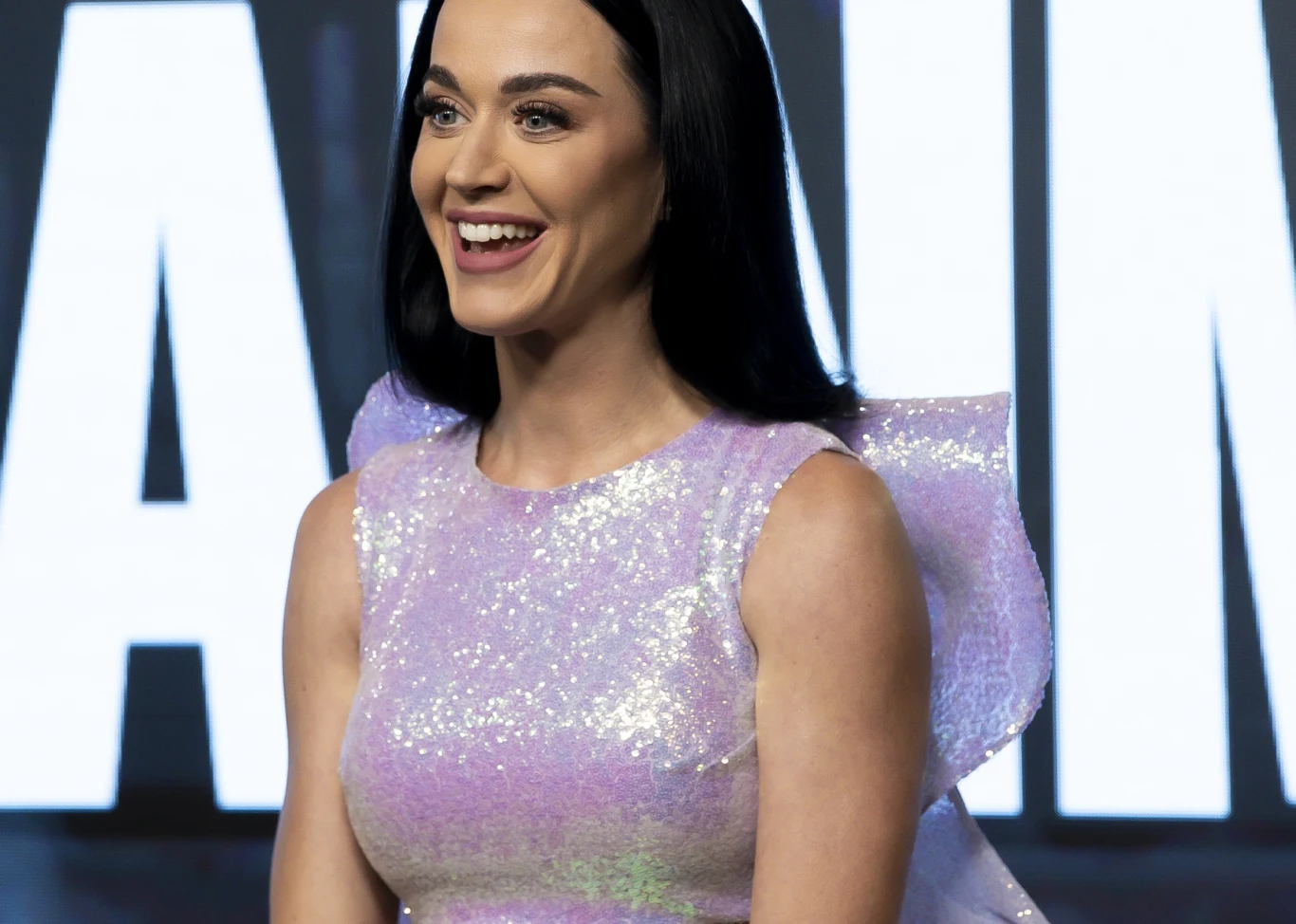 Katy Perry podsumowała końcówkę 2025 roku Uśmiechnięta kobieta o długich, ciemnych włosach w błyszczącej, fioletowej sukni z bufiastymi rękawami na tle jasnych liter.