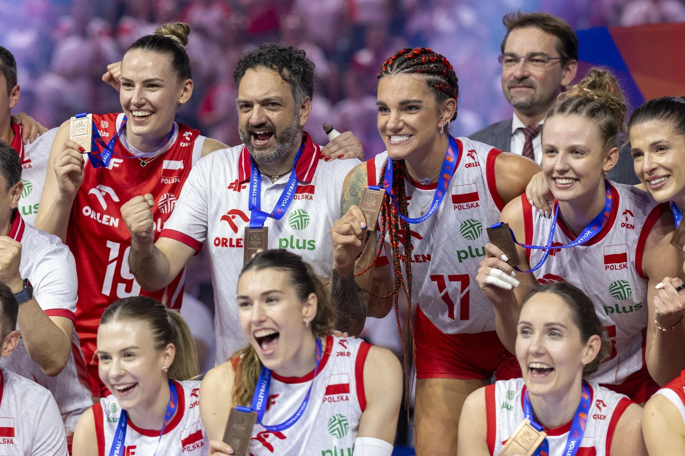 Weronika Centka-Tietianiec w lipcu 2025 roku świętowała brązowy medal Ligi Narodów Grupa zawodniczek siatkarskich ubranych w biało-czerwone stroje sportowe świętuje zdobycie medali. Wszyscy są uśmiechnięci, mają zawieszone na szyjach medale, a wokół panuje radosna atmosfera. W tle widoczni są kibice i sztab szkoleniowy.