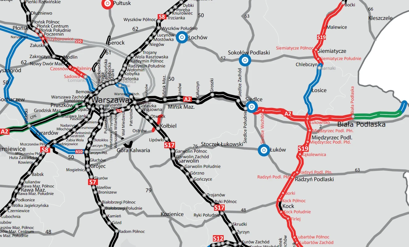 Fragment mapy komunikacyjnej rejonu Warszawy z zaznaczeniem dróg, linii kolejowych oraz głównych węzłów transportowych, z wyraźnie wyróżnionymi trasami oraz nazwami miejscowości wokół stolicy.