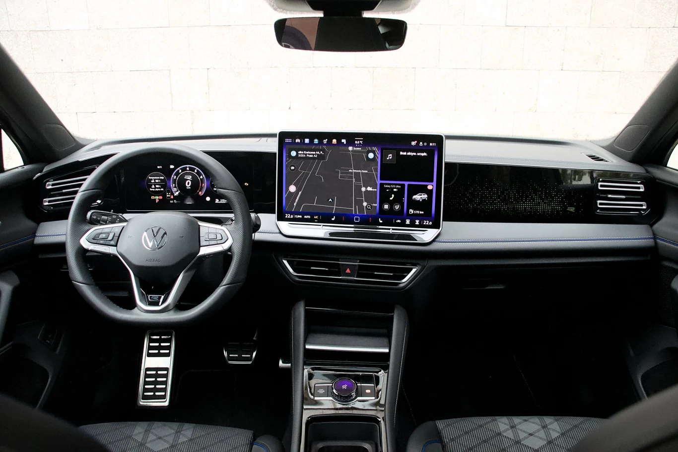 Kokpit nowoczesnego samochodu marki Volkswagen z cyfrowymi ekranami na panelu, dotykowym wyświetlaczem nawigacji, wielofunkcyjną kierownicą oraz eleganckim wykończeniem wnętrza.