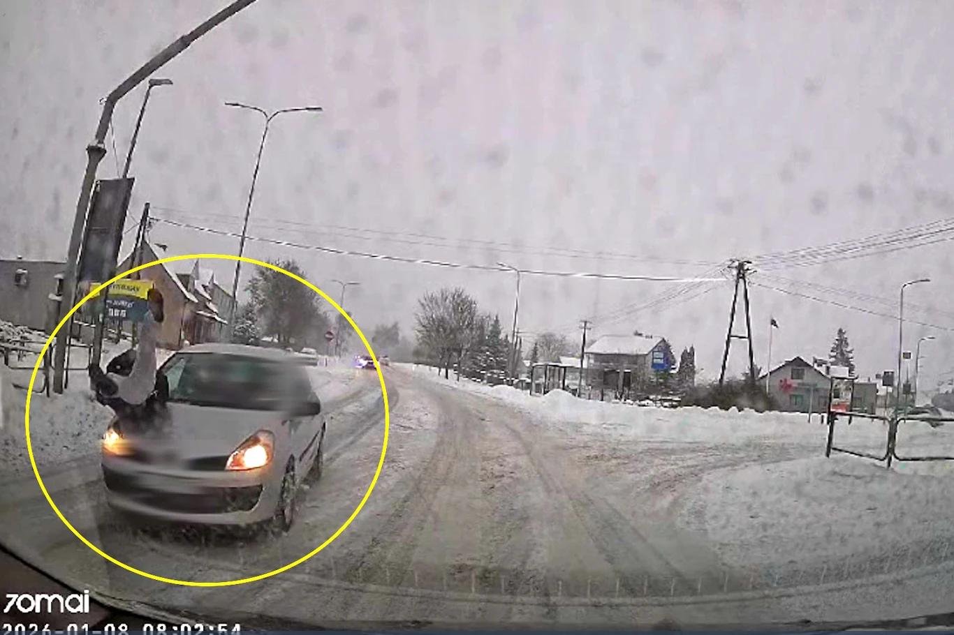 Do potrącenia doszło na przejściu, w trudnych warunkach drogowych Pieszy w momencie potrącenia przez poruszający się samochód osobowy na śnieżnej, oblodzonej drodze w miejskiej okolicy, wokół zimowy krajobraz, ograniczona widoczność przez opady śniegu.