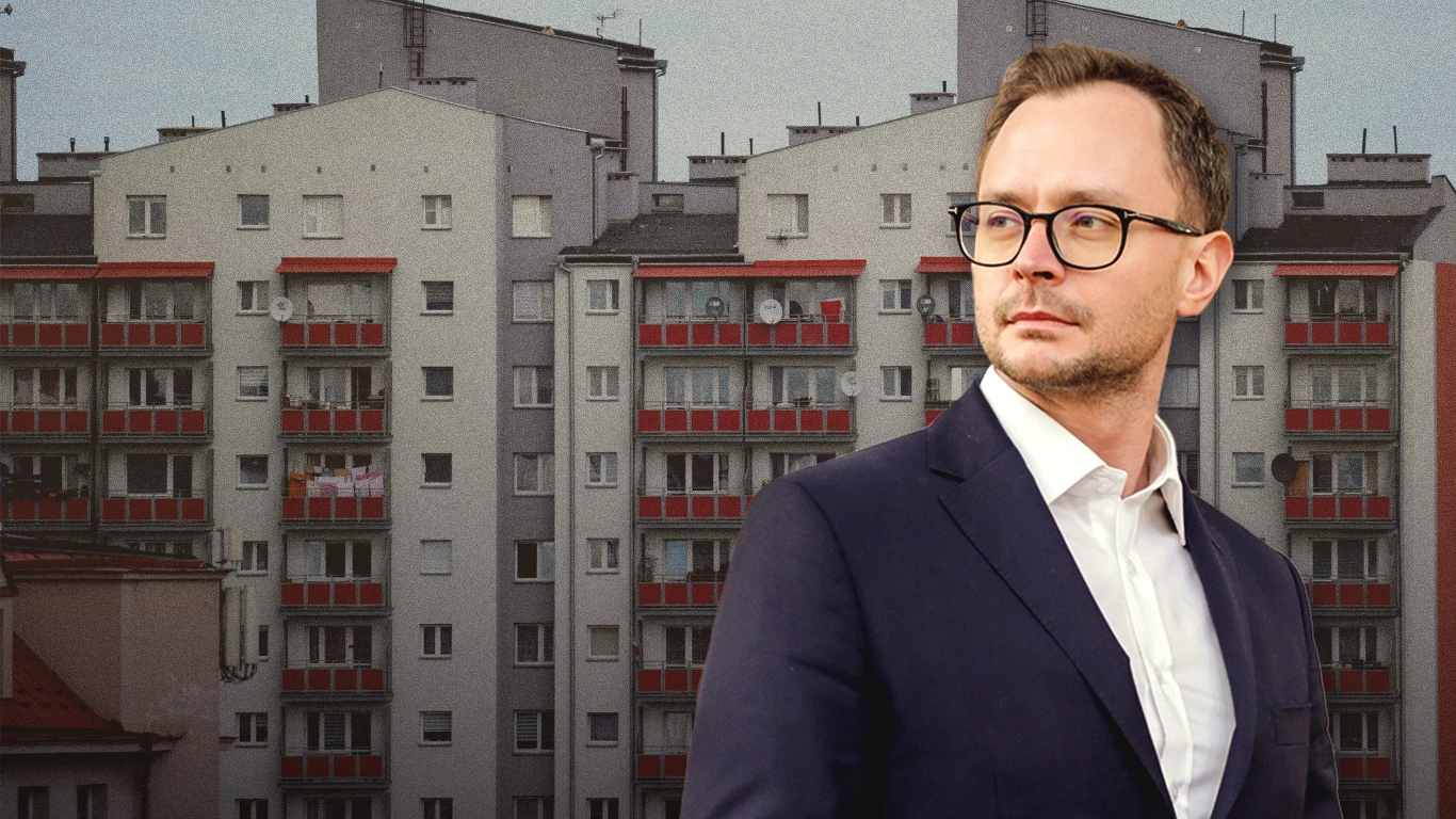 W 2026 zaplanowano rekordowe wydatki na budownictwo społeczne Mężczyzna w garniturze i okularach na tle szarych bloków mieszkalnych, utrzymujących modernistyczny styl architektoniczny, z charakterystycznymi czerwonymi balkonami.