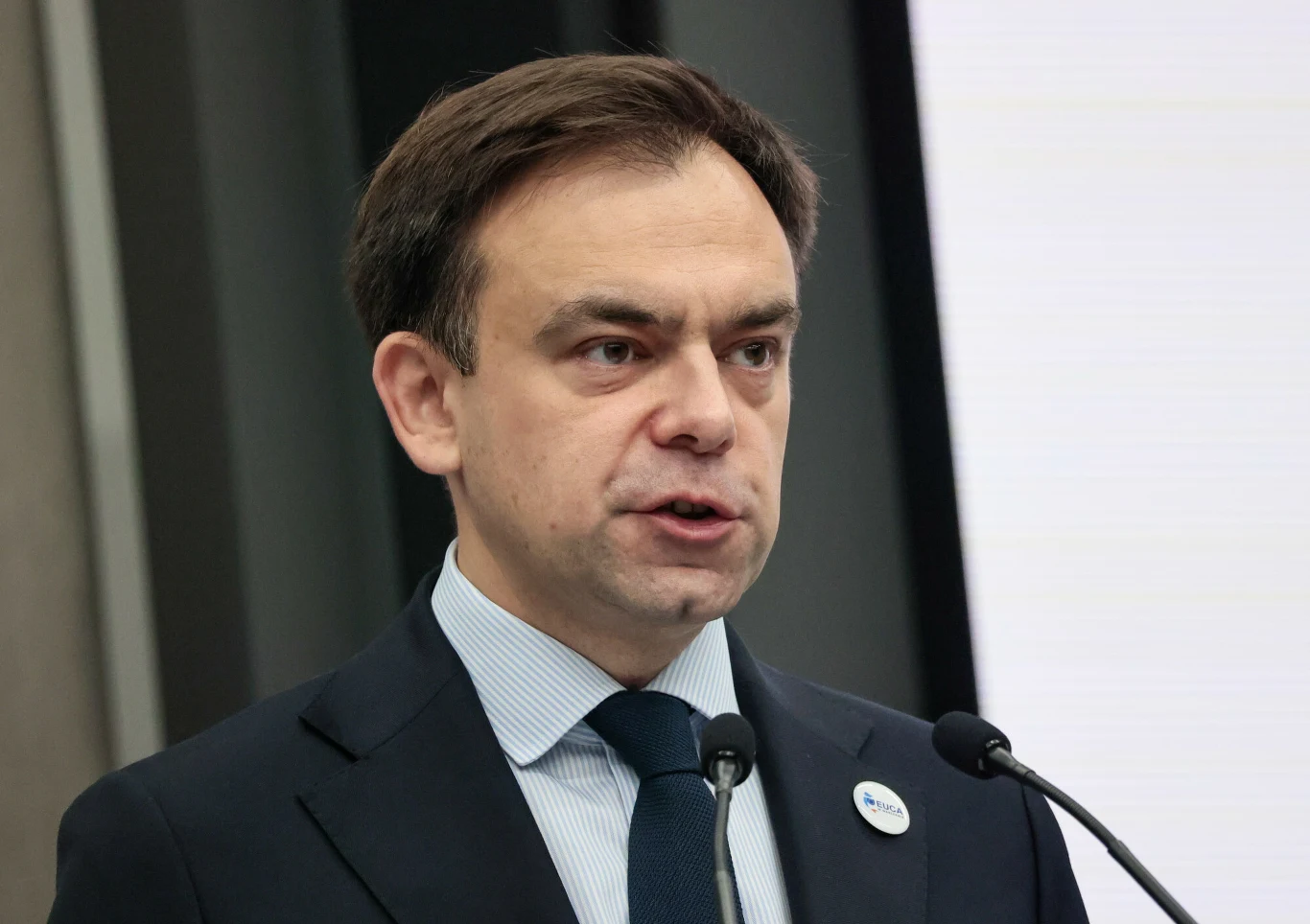 Andrzej Domański podkreślił, że odesłanie przez Karola Nawrockiego ustawy budżetowej do TK spowoduje, że rząd będzie musiał działać w oparciu o projekt ustawy Mężczyzna w garniturze z niebieskim krawatem przemawia do mikrofonu, w tle widoczne są elementy architektury wnętrza i duży ekran lub biała tablica.