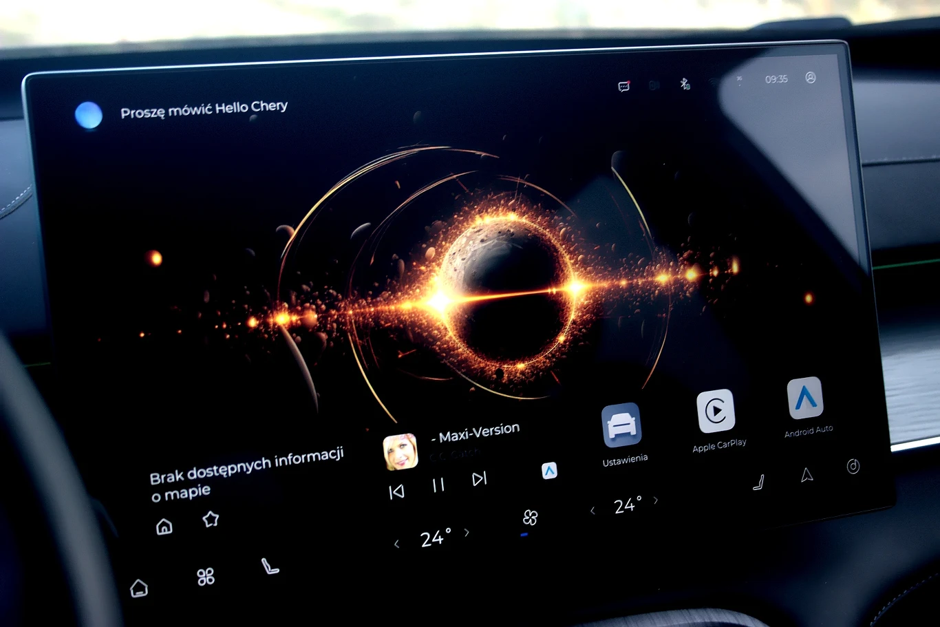 Nowoczesny ekran dotykowy w aucie wyświetlający interfejs systemu multimedialnego z centralnie umieszczonym efektem świetlnym oraz ikonami opcji multimedialnych, nawigacji i ustawień.
