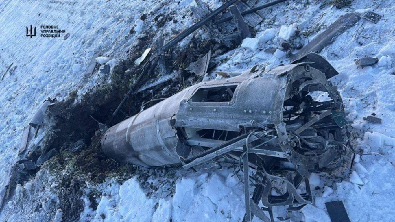 Rosja rozwija Shahedy z napędem odrzutowym i rakietami R-73 Uszkodzony wrak pocisku leży w śniegu, częściowo wbity w ziemię, wokół widoczne szczątki metalu i porwana ziemia, całość sugeruje uderzenie wojskowego pocisku w teren pokryty śniegiem.