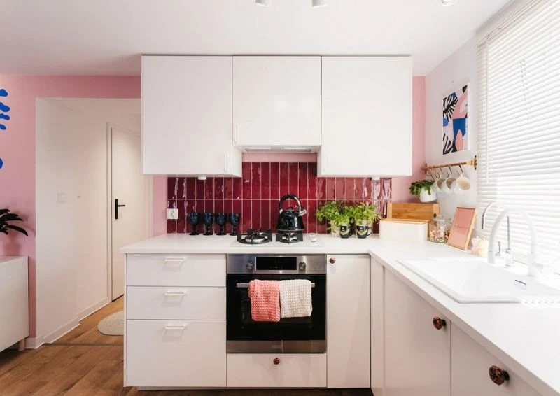 W kuchni główną rolę grają jasne barwy przełamane bordowymi płytkami