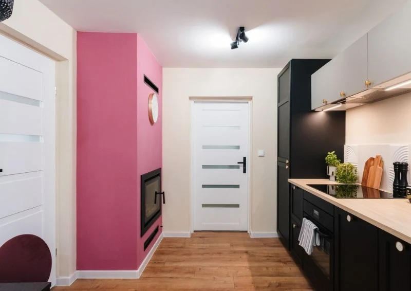 Wyjątkowym akcentem kolorystycznym jest również różowa ściana przy kominku