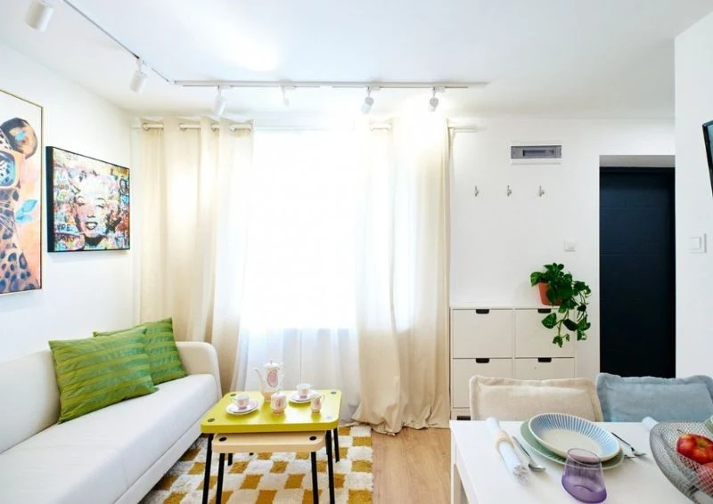 Jasne meble i tekstylia sprawiają, że to przytulne pomieszczenie