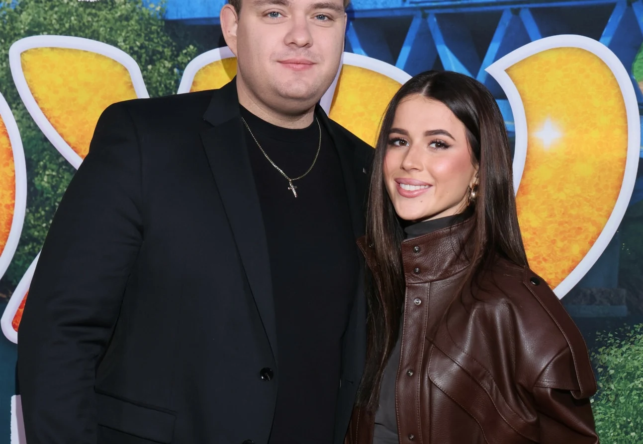 Kevin Mglej i Roksana Węgiel angażują się w wiele projektów Para młodych dorosłych pozuje wspólnie na tle kolorowej, radosnej scenografii; mężczyzna w ciemnej marynarce i kobieta w brązowej kurtce uśmiechają się, tworząc przyjazny i elegancki klimat fotografii.