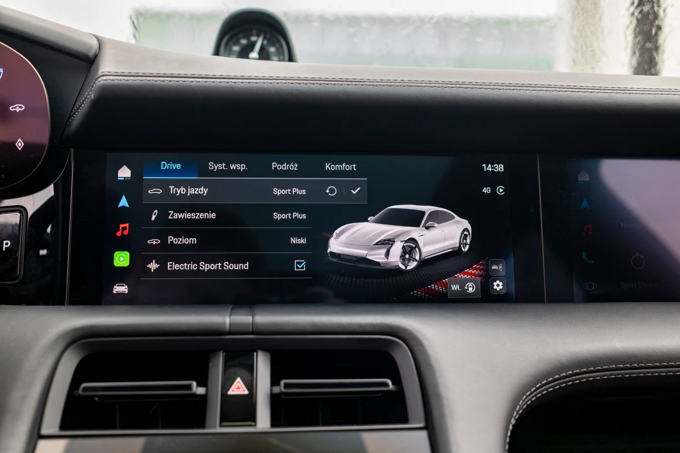 Wnętrze samochodu z cyfrowym panelem sterowania na konsoli środkowej, wyświetlającym ustawienia jazdy, zawieszenia, poziomu oraz opcję Electric Sport Sound wraz z wizualizacją sportowego auta.