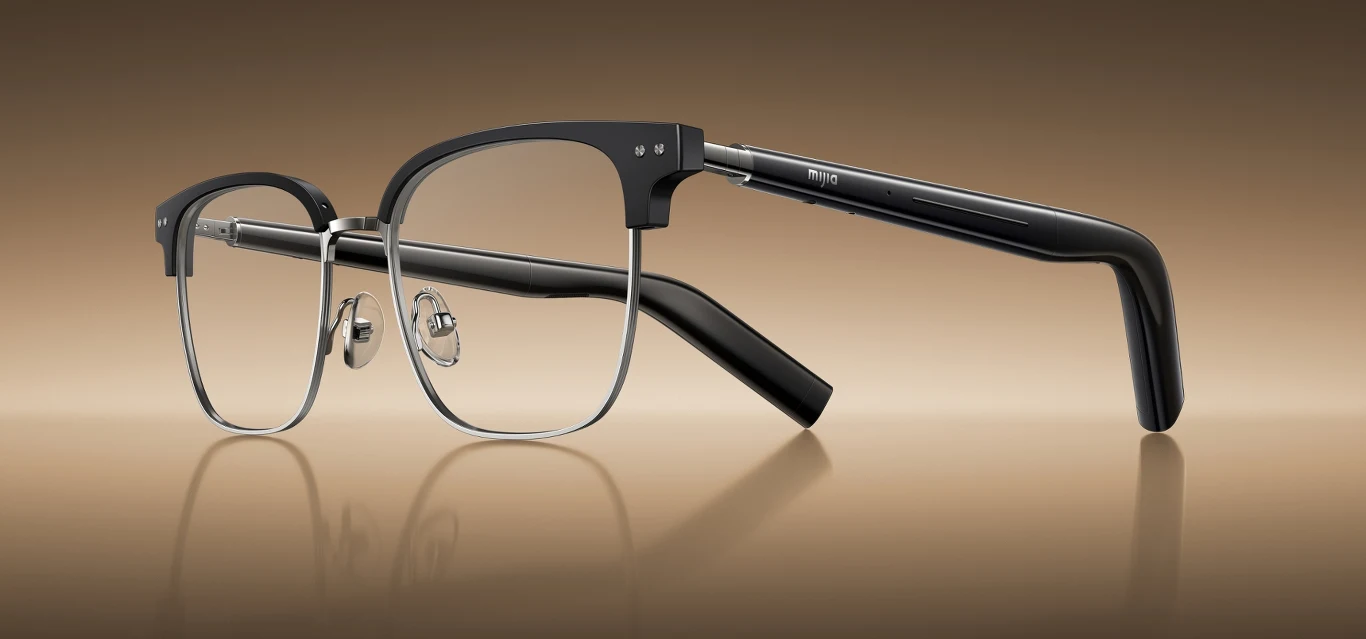 Metalowe okulary korekcyjne w stylu retro, z czarnym wykończeniem górnej części oprawek i klasycznymi zausznikami, ustawione na gładkim, jasnobrązowym tle z lekko odbijającą powierzchnią.