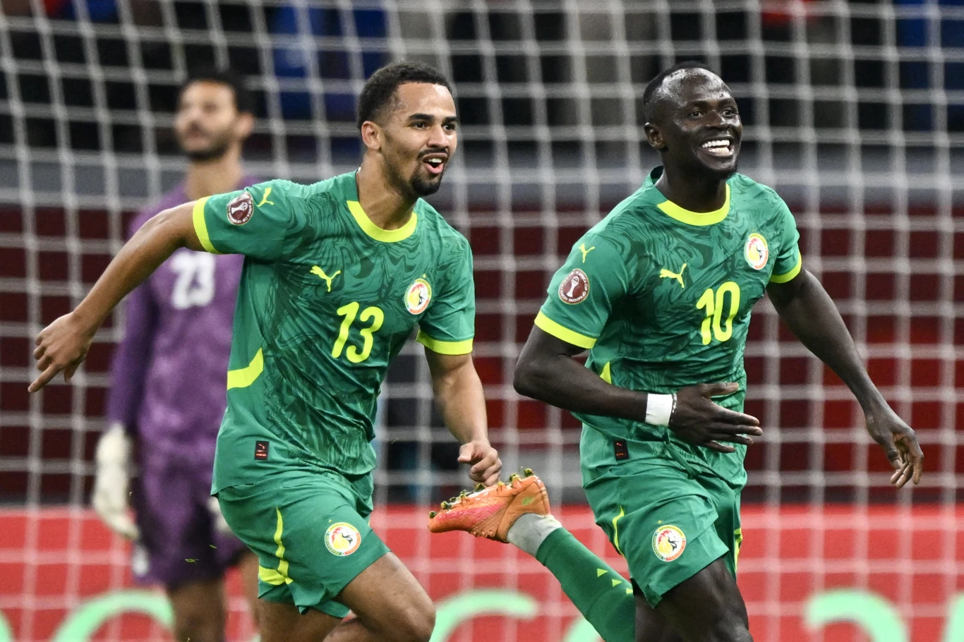 Sadio Mane ma poprowadzić Senegal do drugiego Pucharu Narodów Afryki Dwóch piłkarzy reprezentacji Senegalu w zielonych strojach cieszy się z sukcesu na boisku, w tle widoczny bramkarz stojący przy bramce.