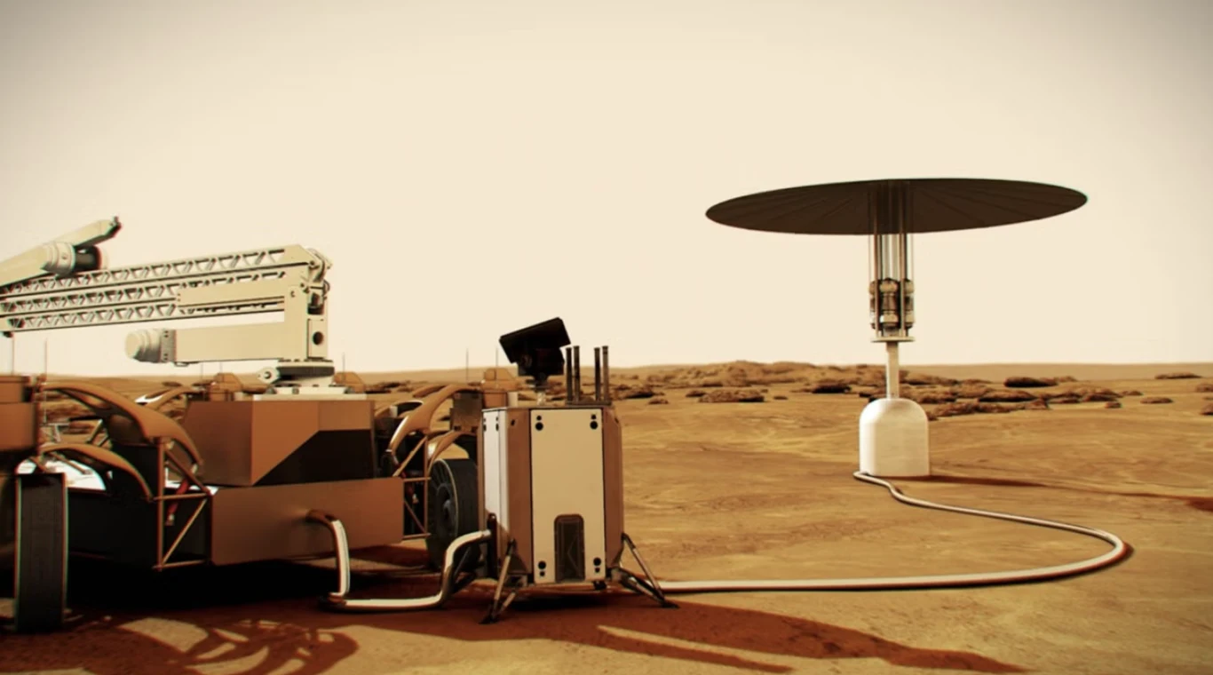 Reaktor obok flagi. NASA zapowiada "nuklearne serce" dla bazy Artemis Łazik kosmiczny połączony przewodem z niewielką elektrownią o dużym, okrągłym panelu na pustynnym, marsjańskim krajobrazie.