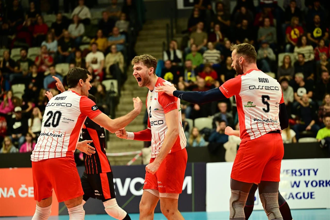 Jakub Bucki (z prawej) gra w Resovii od 2021 r. Grupa siatkarzy w biało-czerwonych strojach drużyny Asseco Resovia świętuje zdobycie punktu podczas meczu na arenie sportowej, wokół rozległe trybuny wypełnione kibicami.