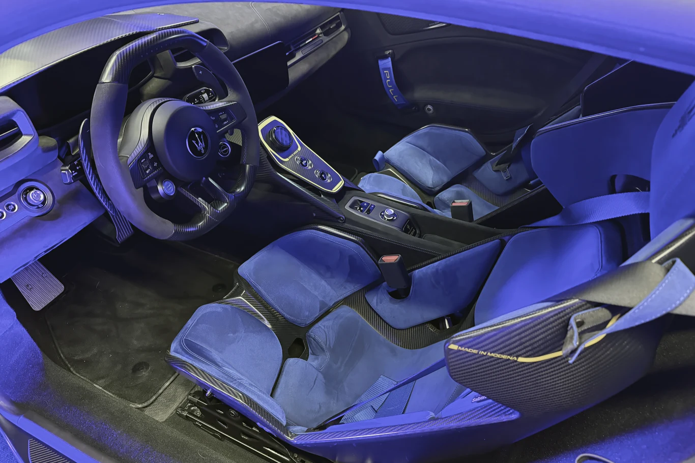 Nowoczesne, sportowe wnętrze samochodu z kubełkowymi fotelami, obszyciem z alcantary oraz elementami wykończenia z włókna węglowego. Kierownica o sportowym charakterze i zaawansowana konsola centralna podkreślają ekskluzywny styl pojazdu.