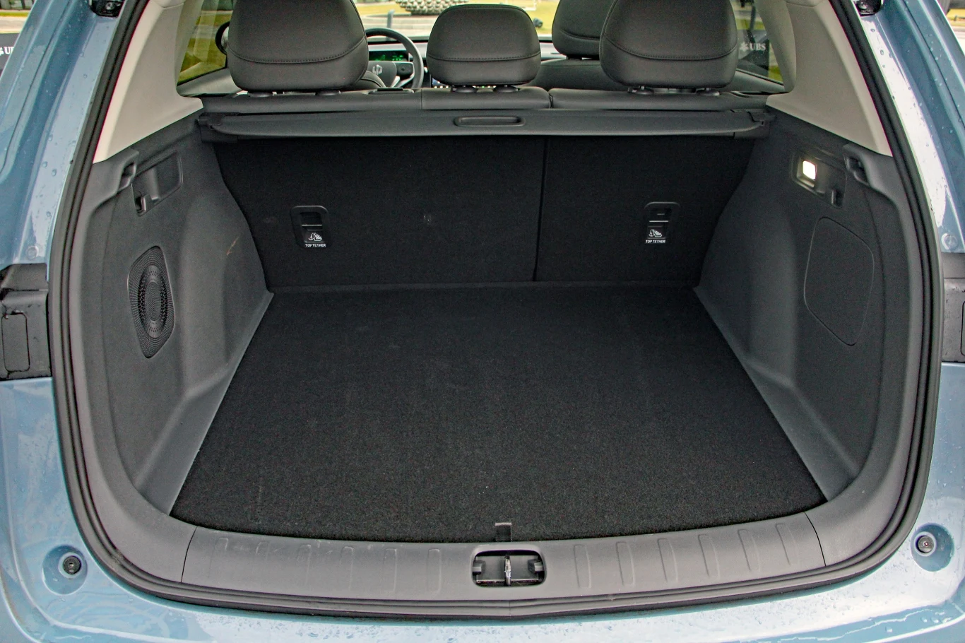 Pojemny bagażnik samochodu osobowego z widocznymi składanymi oparciami tylnej kanapy, oświetleniem bocznym oraz solidnym wykończeniem wnętrza bagażnika.