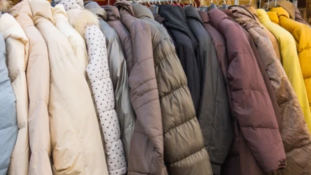 Wieszak pełen puchowych kurtek zimowych w różnych kolorach